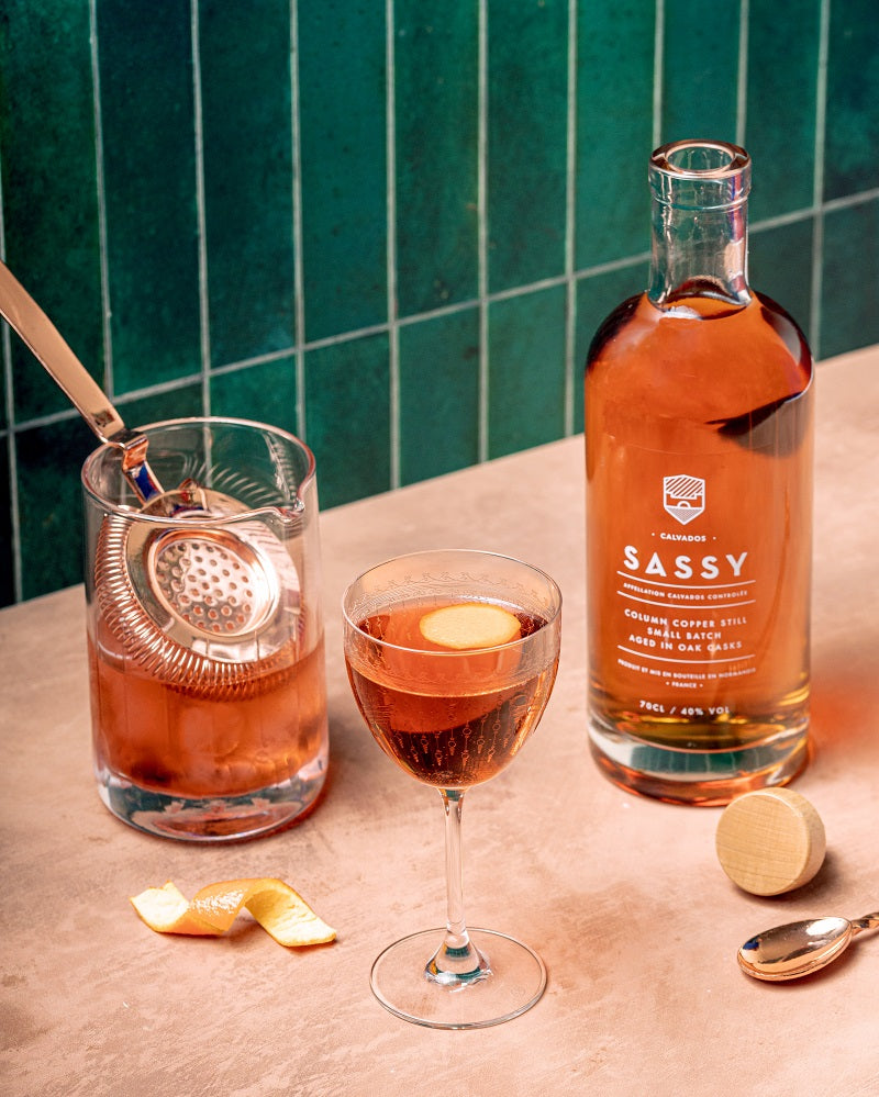 A bottle of calvados with cocktail glass and strainer