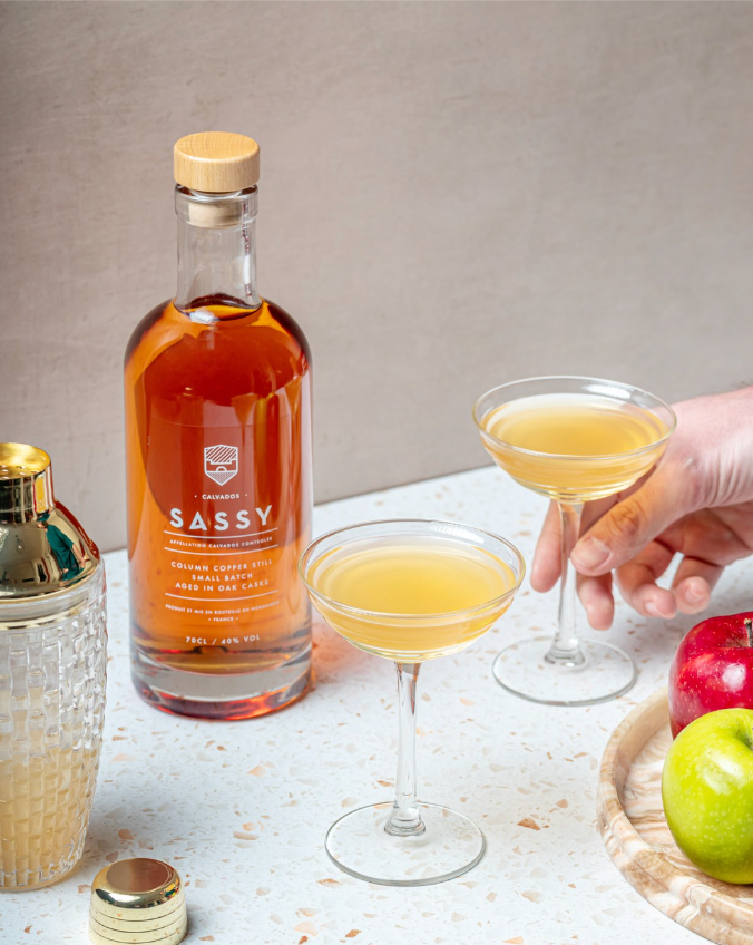 Two calvados cocktails next to a bottle of Maison Sassy calvados